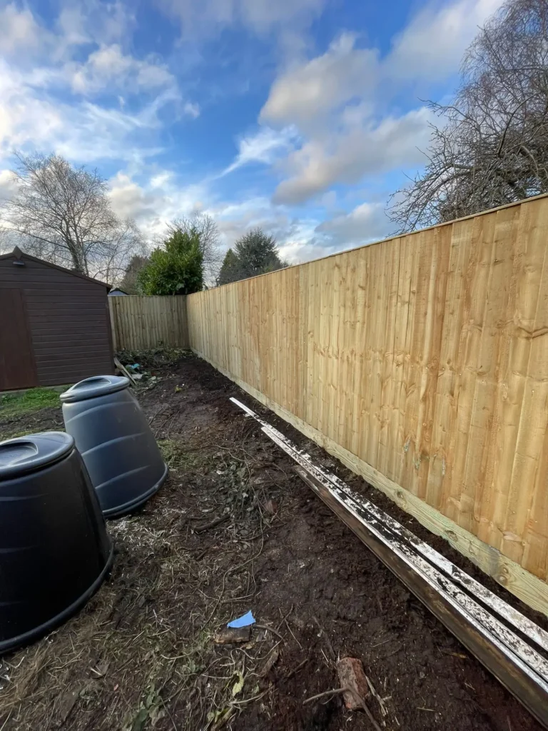 Newly installed wooden panel fence boundary along a residential garden border.